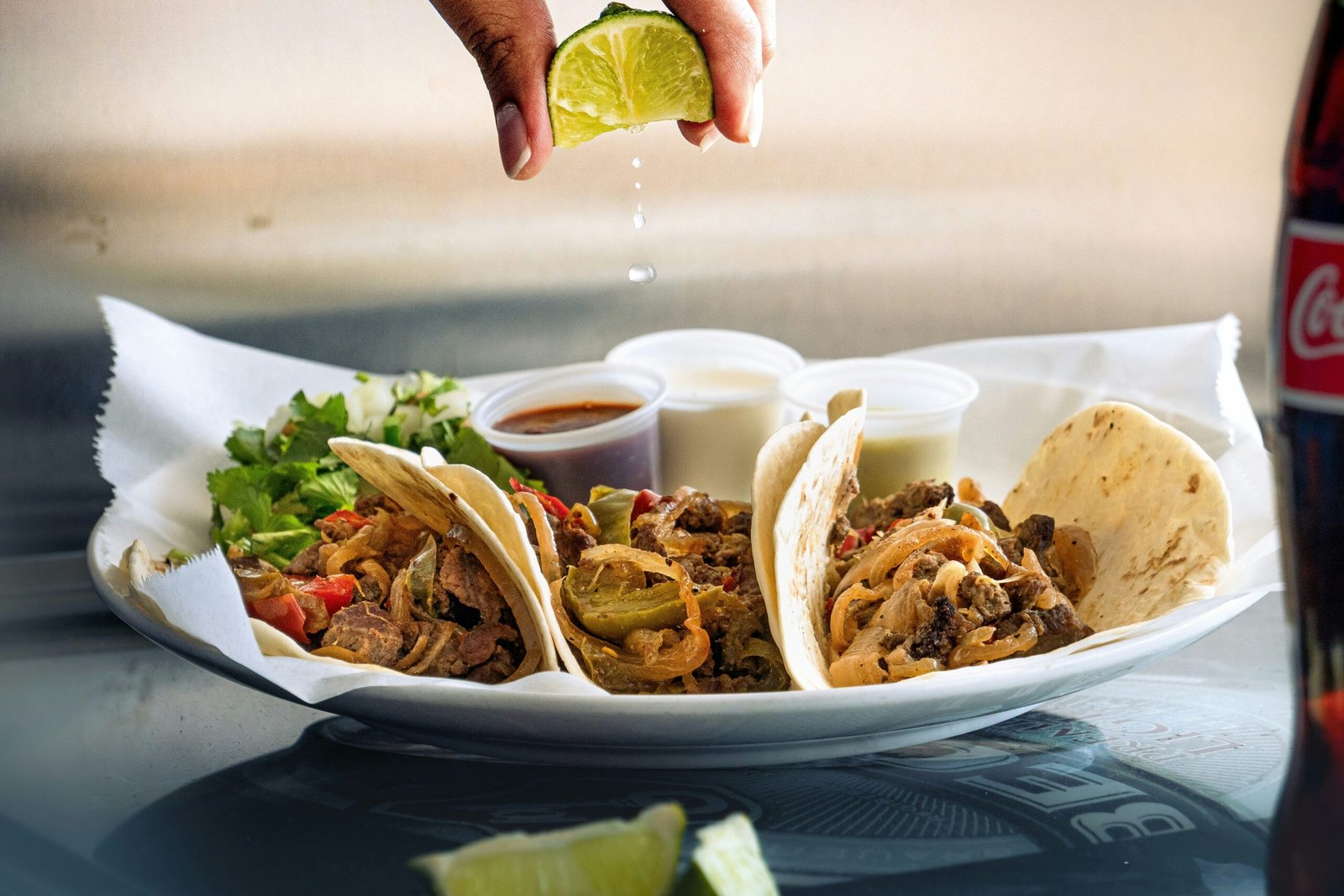 a plate of tacos with a lime being drizzled on top